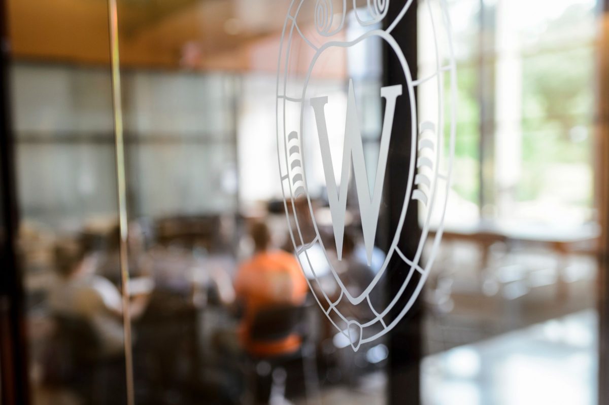 uw crest in white on glass wall outside a conference room