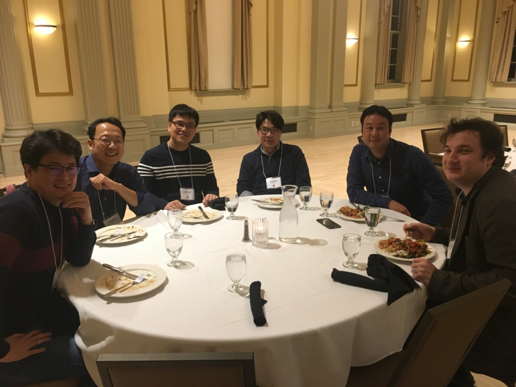 Students eat at a table together and smile at the camera