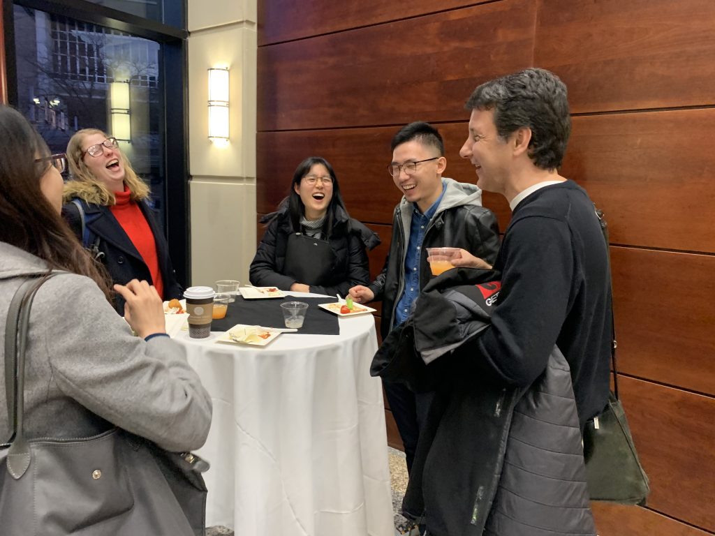 People talk with each other at the reception following a presentation they just attended over food