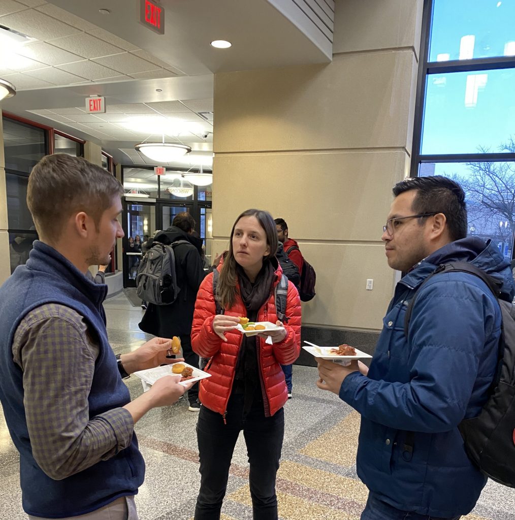 People talk with each other at the reception following a presentation they just attended over food