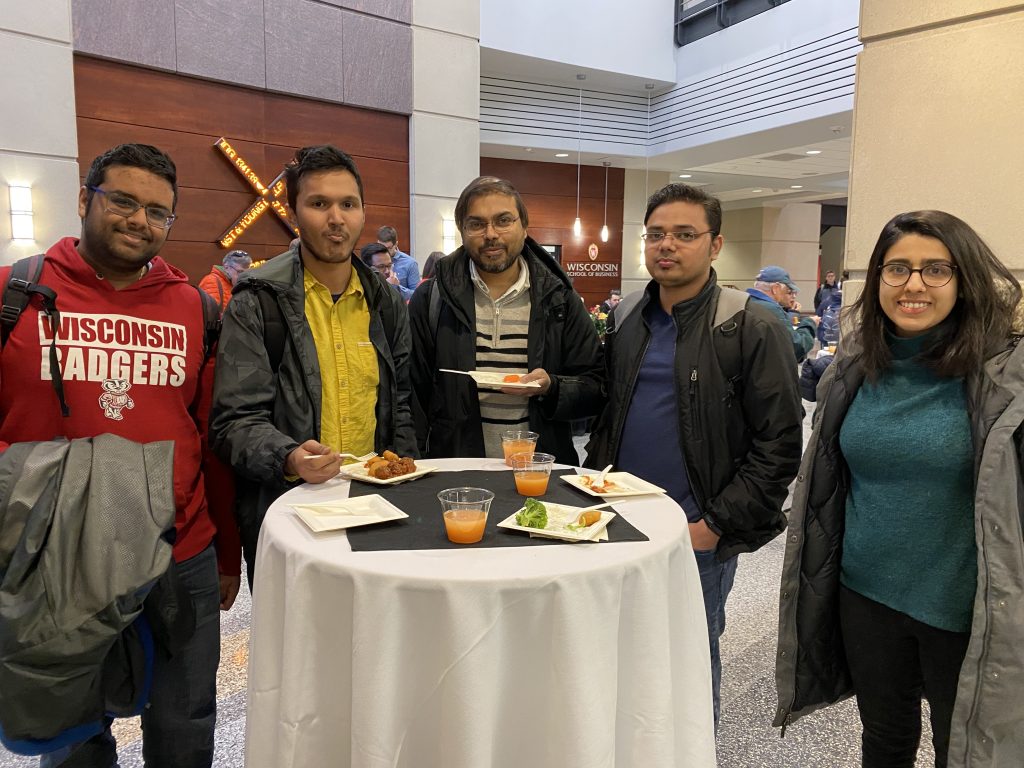 students smile at the camera at a reception after listening to an economics presentation