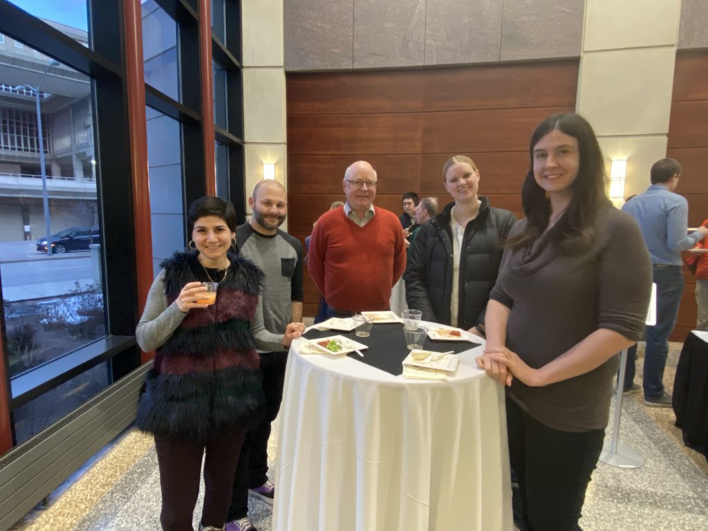 People talk with each other at the reception following a presentation they just attended over food