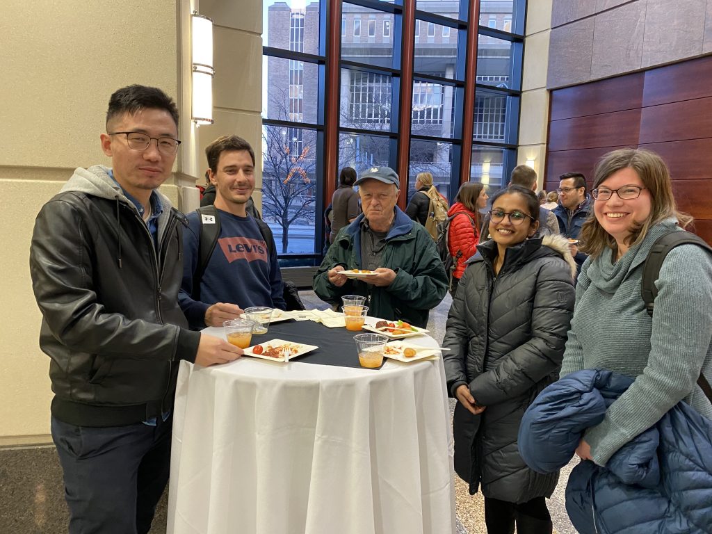 People talk with each other at the reception following a presentation they just attended over food