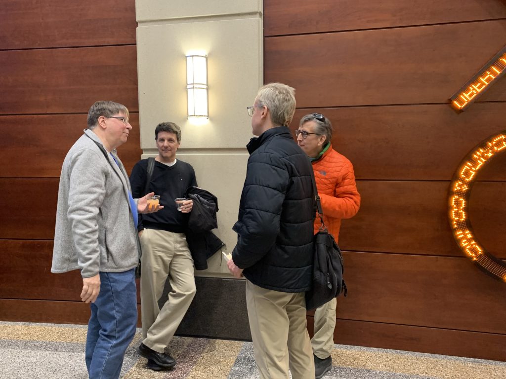 People talk with each other at the reception following a presentation they just attended over food