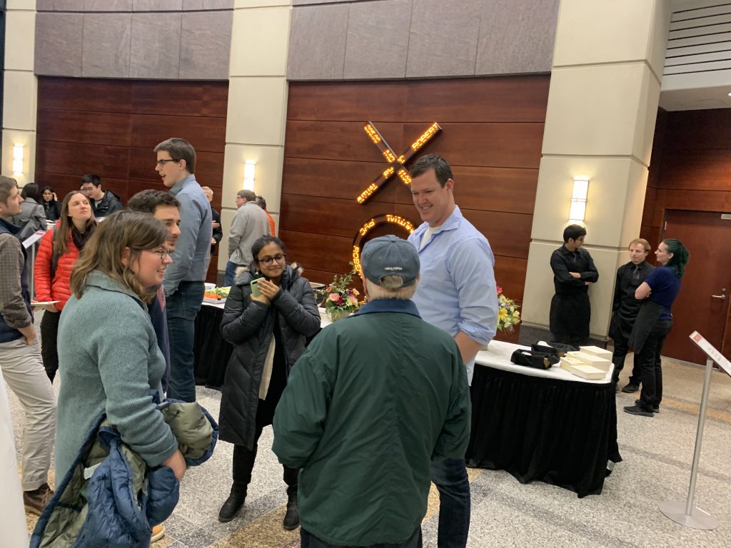 People talk with each other at the reception following a presentation they just attended over food